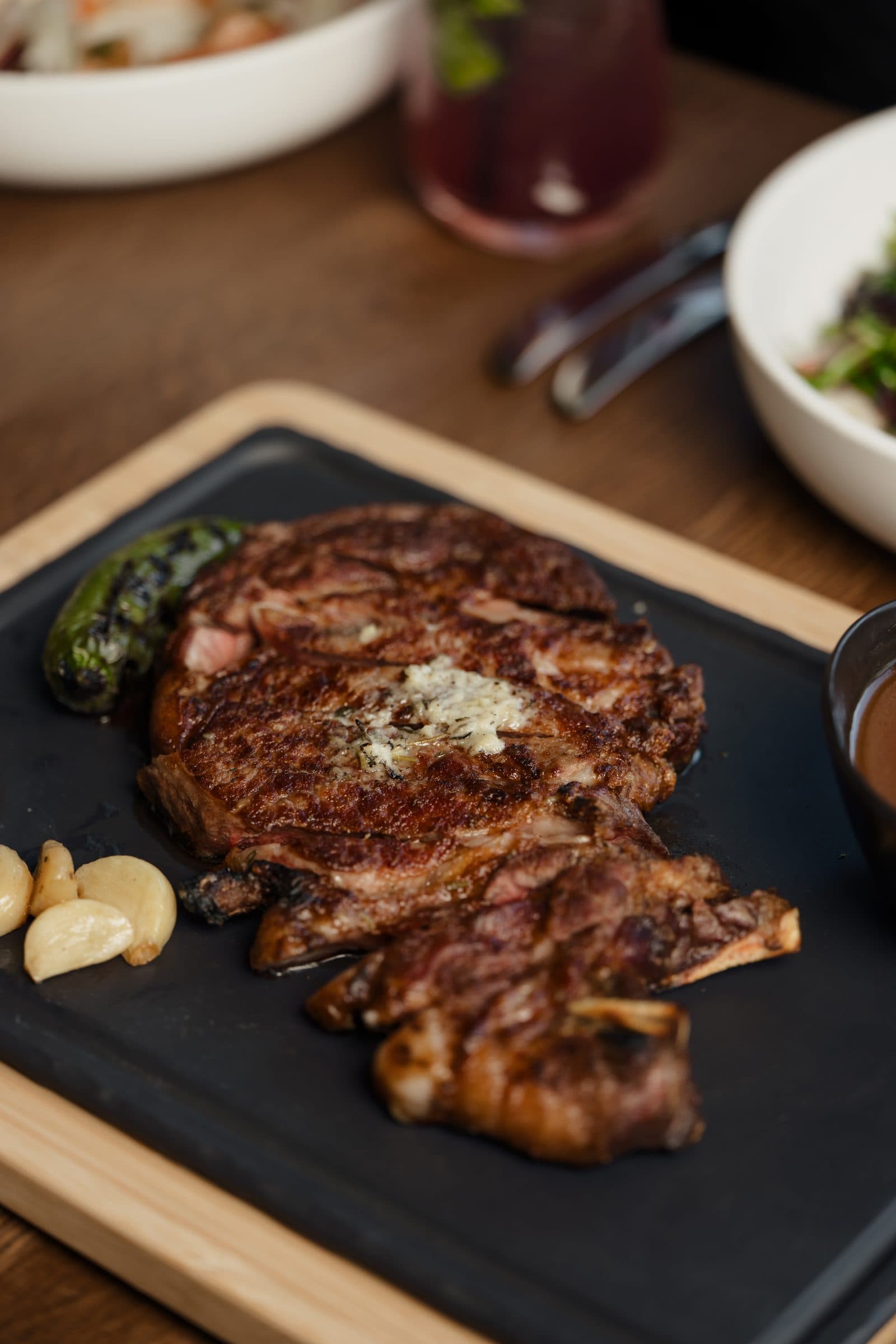 Dry-aged ribeye with herb butter on a wooden serving board