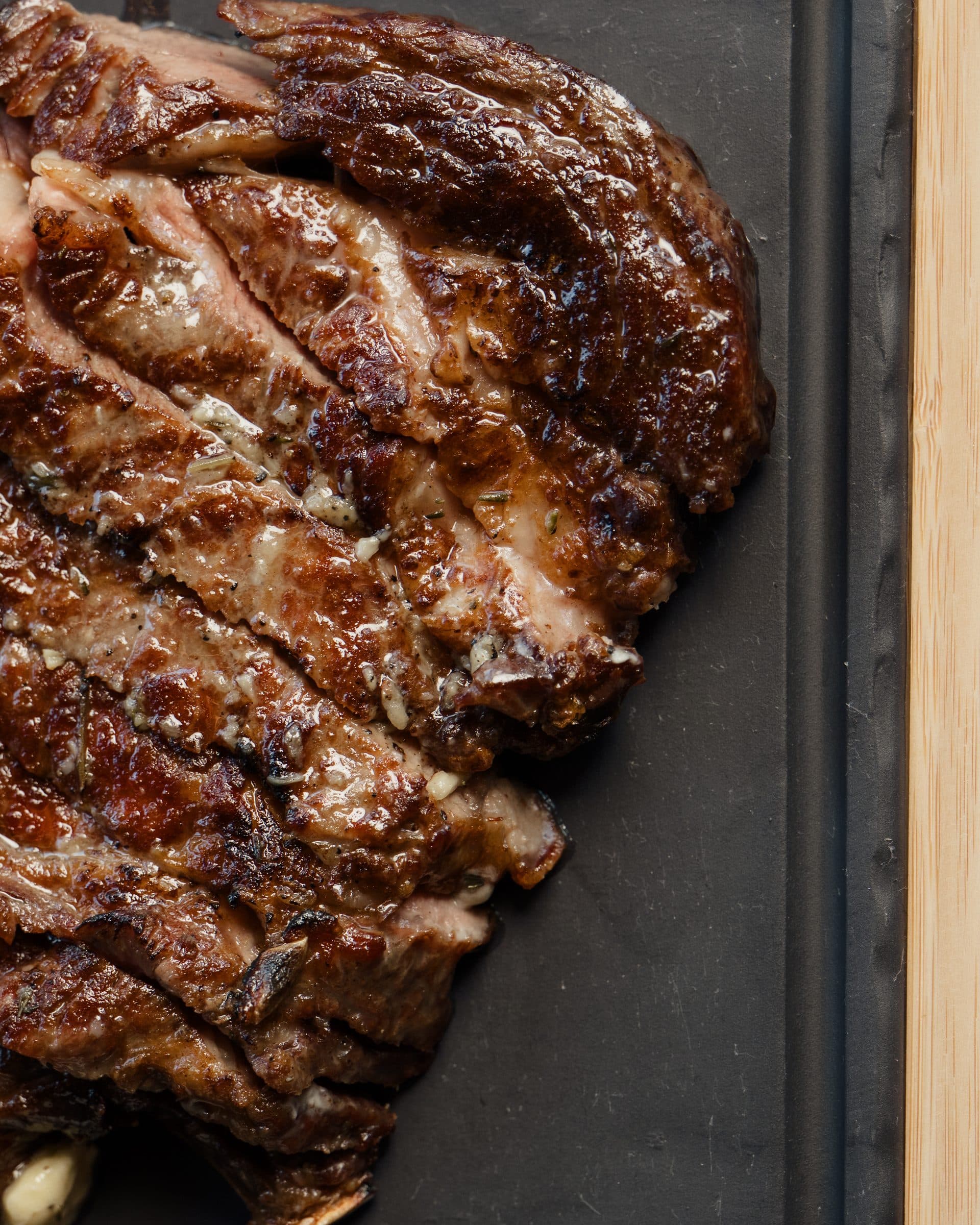 Close-up of a grilled dry-aged ribeye, sliced on the board